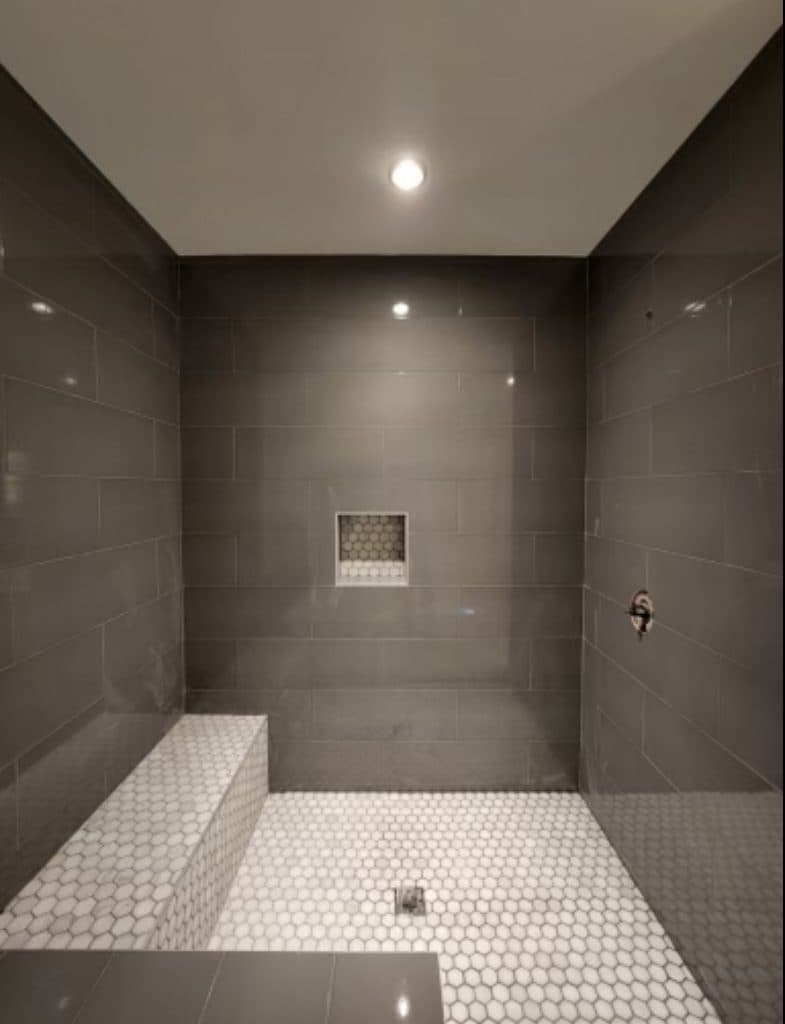 Gray tile shower with bench and white hex floor