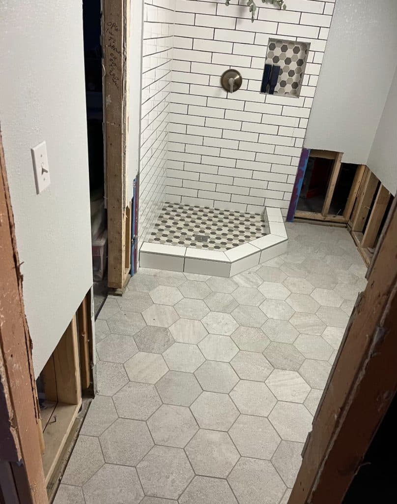Bathroom remodel in progress with hex floor and subway tile shower
